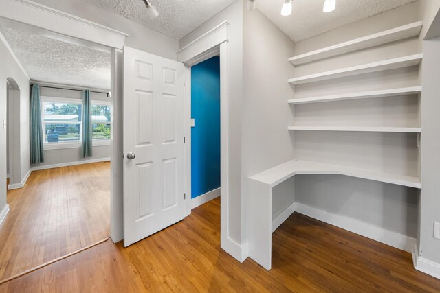 interior space featuring a textured ceiling and wood-type flooring