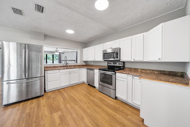 kitchen featuring ceiling fan, white cabinets, appliances with stainless steel finishes, light hardwood / wood-style floors, and sink