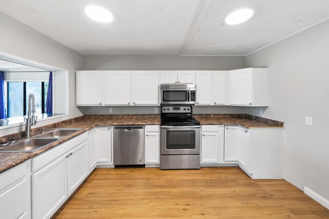 kitchen featuring sink, appliances with stainless steel finishes, light hardwood / wood-style floors, a textured ceiling, and white cabinetry