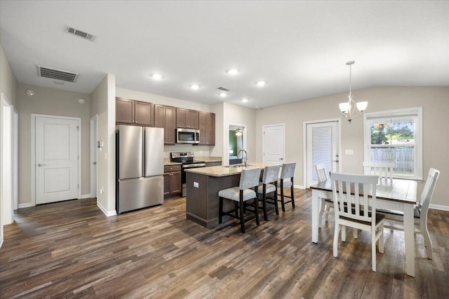 kitchen with pendant lighting, an island with sink, stainless steel appliances, and dark wood-type flooring