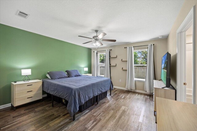 bedroom with a textured ceiling, ceiling fan, and dark hardwood / wood-style flooring