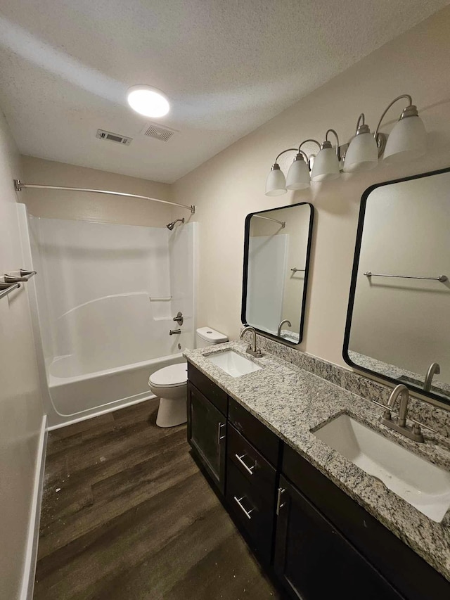 full bathroom featuring toilet, shower / bathtub combination, vanity, hardwood / wood-style flooring, and a textured ceiling