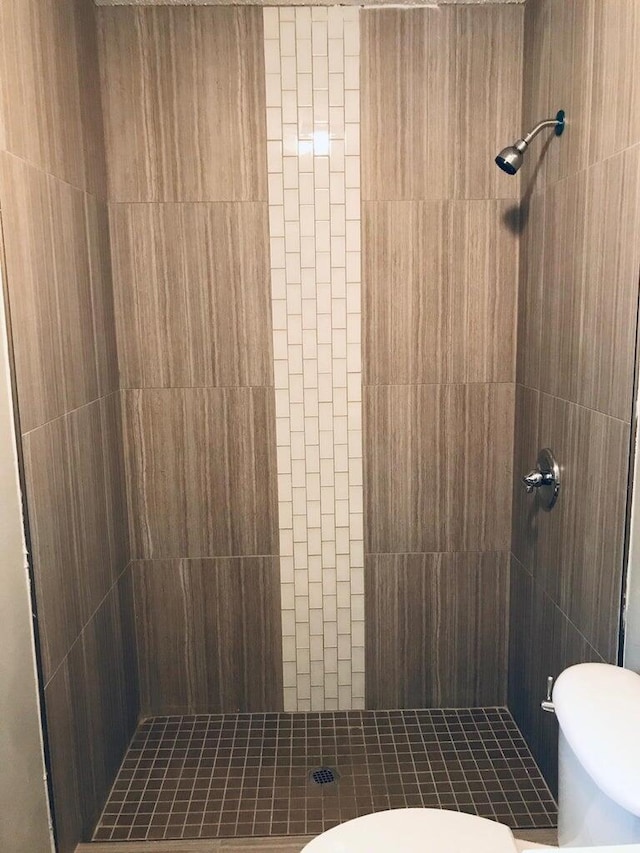 bathroom featuring tiled shower and toilet