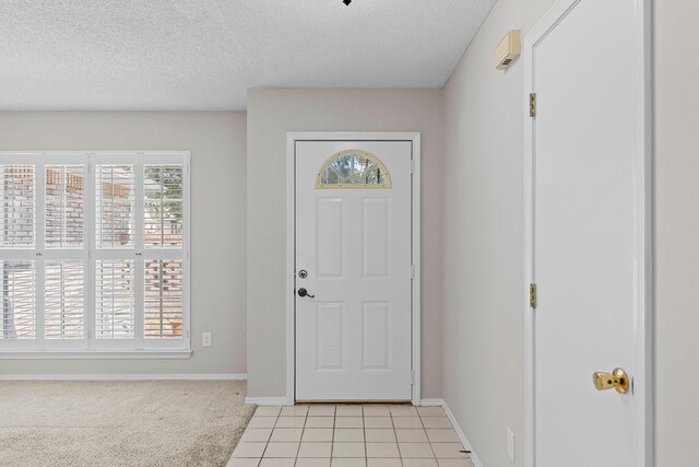 carpeted foyer featuring a textured ceiling and a healthy amount of sunlight