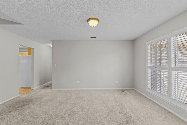 carpeted empty room with a textured ceiling