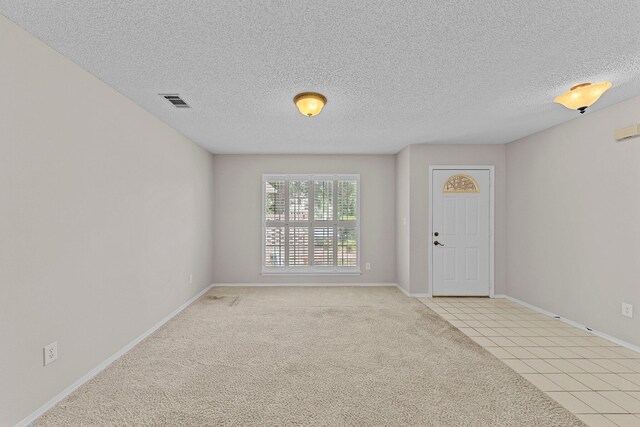 spare room with a textured ceiling and light colored carpet