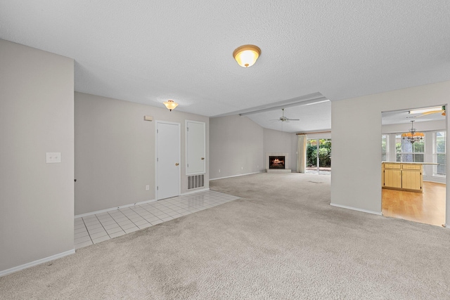 unfurnished living room featuring ceiling fan with notable chandelier, a textured ceiling, and light colored carpet