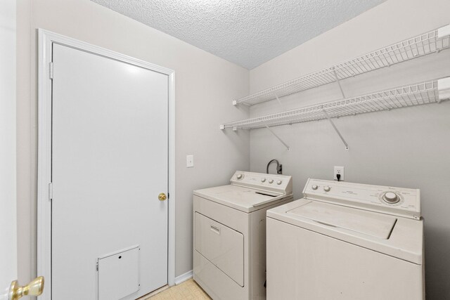 laundry room featuring a textured ceiling and washing machine and dryer