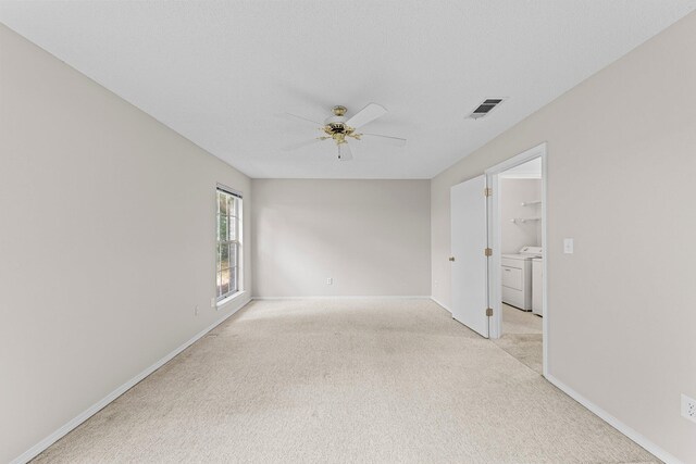 spare room featuring ceiling fan, separate washer and dryer, and light carpet