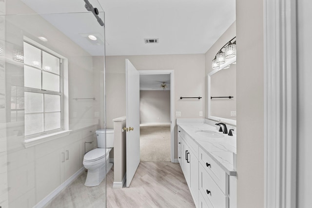 bathroom featuring vanity, toilet, wood-type flooring, and ceiling fan