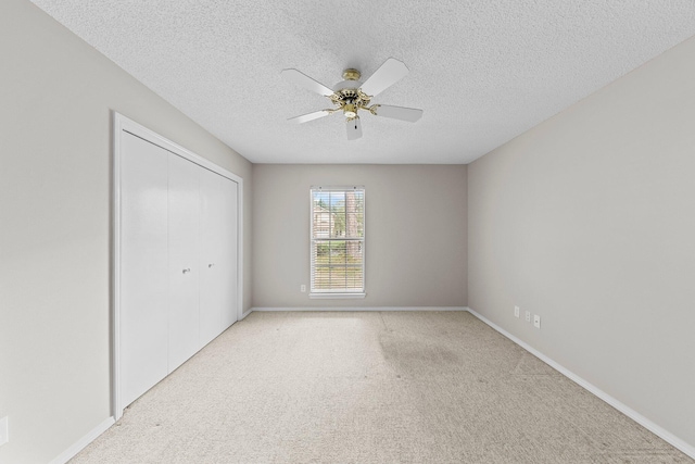 empty room featuring ceiling fan, light colored carpet, and a textured ceiling