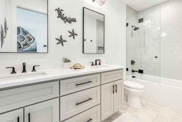 full bathroom featuring bath / shower combo with glass door, a sink, toilet, and double vanity