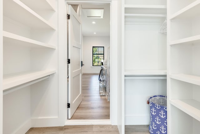 walk in closet with attic access and wood finished floors