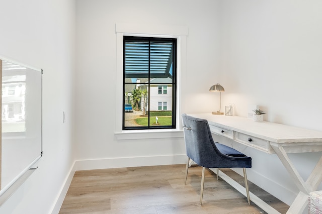 office area featuring built in study area, baseboards, and wood finished floors