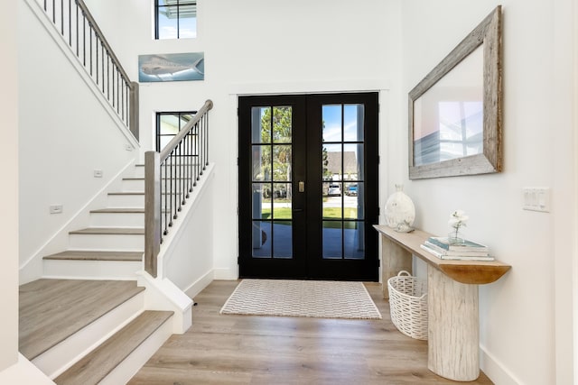 foyer with stairs, french doors, wood finished floors, and baseboards