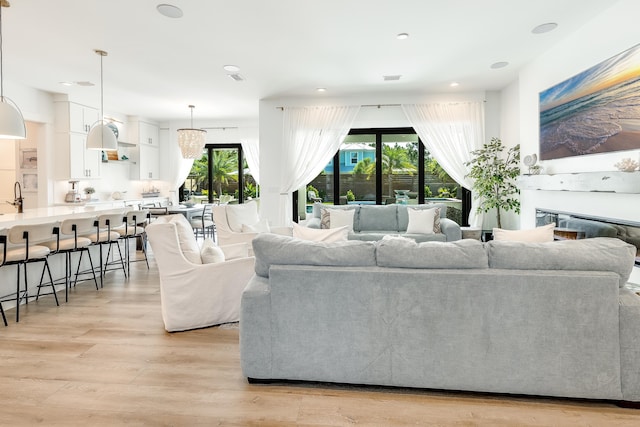 living area with a glass covered fireplace, visible vents, and light wood-style floors