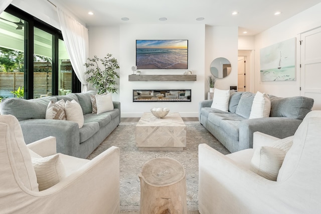 living area with a glass covered fireplace, wood finished floors, and recessed lighting