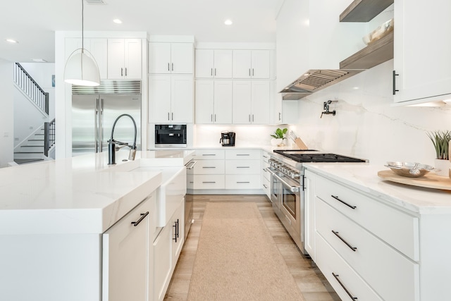 kitchen featuring premium appliances, a sink, wall chimney exhaust hood, and tasteful backsplash