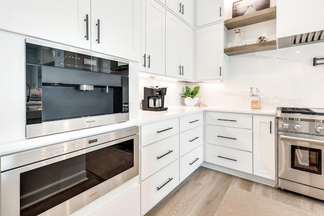 kitchen featuring stainless steel appliances, light countertops, white cabinets, and decorative backsplash