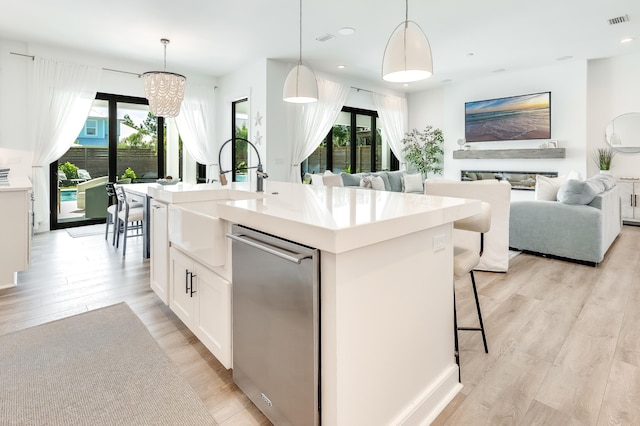 kitchen featuring a sink, visible vents, white cabinets, light wood-style floors, and light countertops