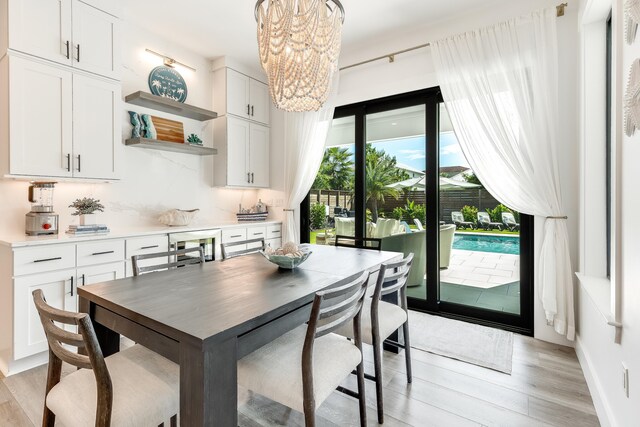 dining room with light wood-style floors and an inviting chandelier