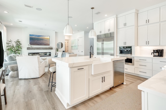 kitchen with open floor plan, stainless steel appliances, visible vents, and white cabinetry