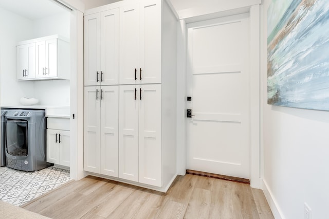 interior space featuring white cabinets, washer / dryer, light wood finished floors, and light countertops