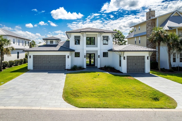 view of front of property with a garage, a tile roof, french doors, decorative driveway, and a front yard