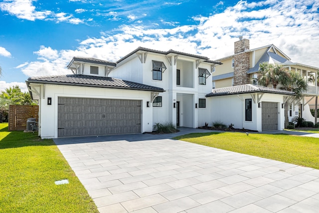 view of front of house featuring a garage, a tiled roof, and a front lawn