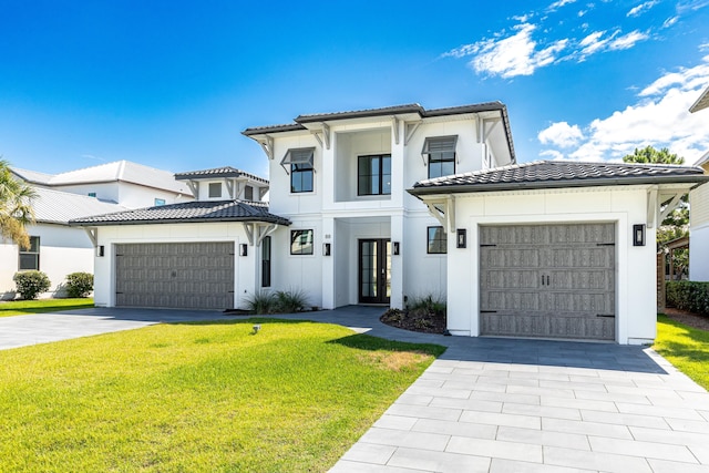 view of front of home featuring a garage, a tiled roof, decorative driveway, and a front yard