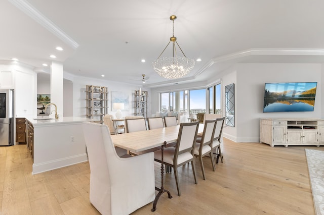 dining space with light hardwood / wood-style floors, sink, crown molding, and a notable chandelier