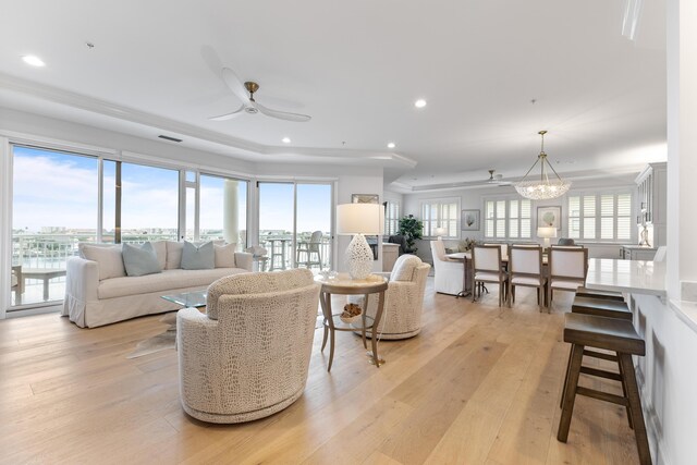 living room with light wood-type flooring and ceiling fan with notable chandelier