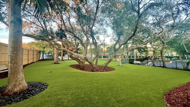 view of home's community featuring a lawn and fence