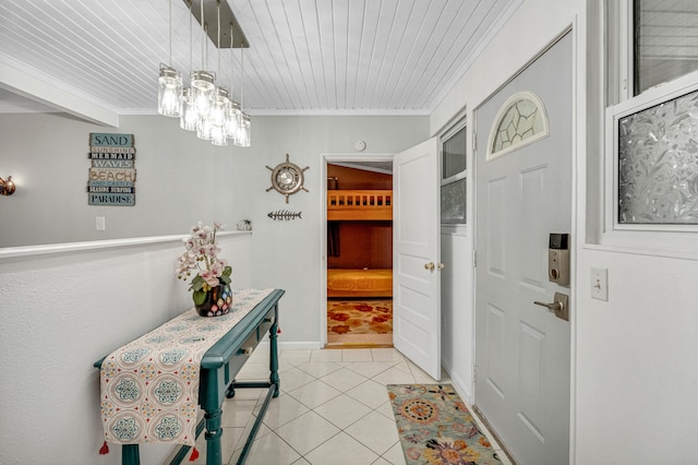 tiled foyer entrance featuring wood ceiling, crown molding, and an inviting chandelier