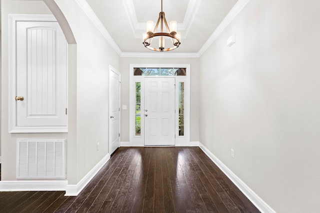 entrance foyer featuring ornamental molding, a raised ceiling, a chandelier, and dark hardwood / wood-style floors