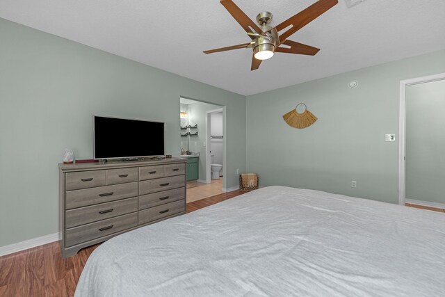 bedroom featuring light wood-type flooring, ensuite bathroom, and ceiling fan