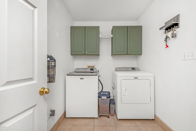 clothes washing area with washer and clothes dryer, light tile patterned floors, cabinets, and a textured ceiling