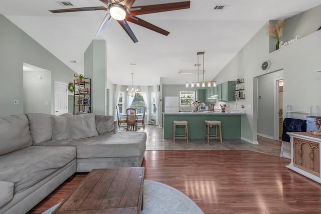 living room featuring ceiling fan with notable chandelier, high vaulted ceiling, and light hardwood / wood-style floors