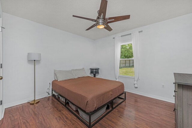 bedroom featuring a textured ceiling, ceiling fan, and dark hardwood / wood-style flooring