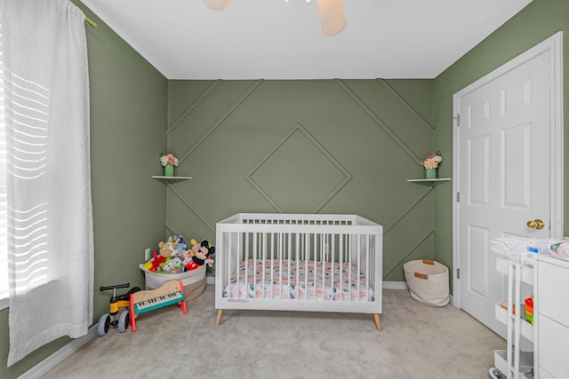 carpeted bedroom with ceiling fan and a crib