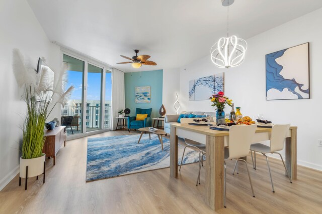 dining space featuring ceiling fan with notable chandelier, light hardwood / wood-style flooring, and expansive windows