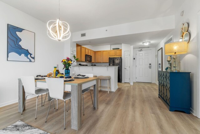 dining space with light wood-type flooring and a chandelier