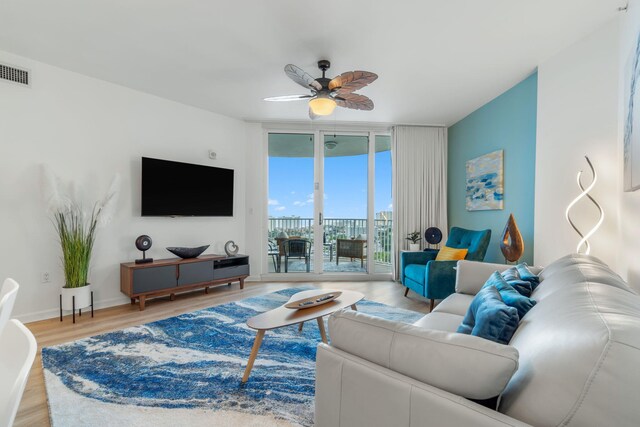 living room featuring floor to ceiling windows, ceiling fan, and light wood-type flooring