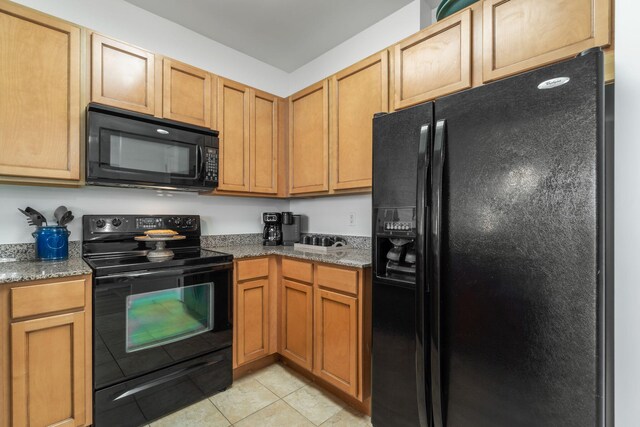 kitchen with black appliances, light tile patterned floors, and stone counters