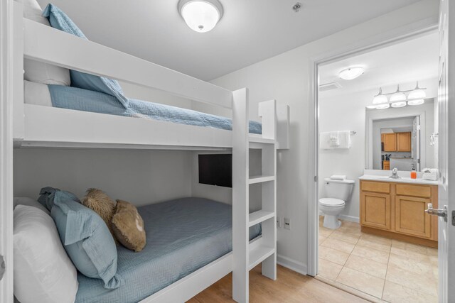 tiled bedroom featuring connected bathroom and sink