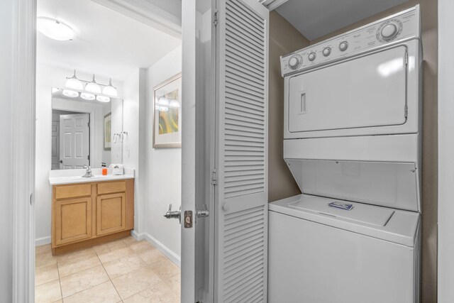 washroom with sink, light tile patterned floors, and stacked washer and dryer