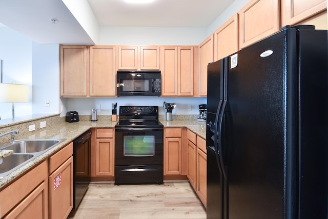 kitchen featuring light wood-type flooring, light stone countertops, sink, black appliances, and kitchen peninsula