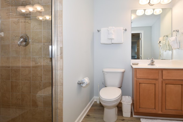 bathroom featuring vanity, a shower stall, toilet, and wood finished floors