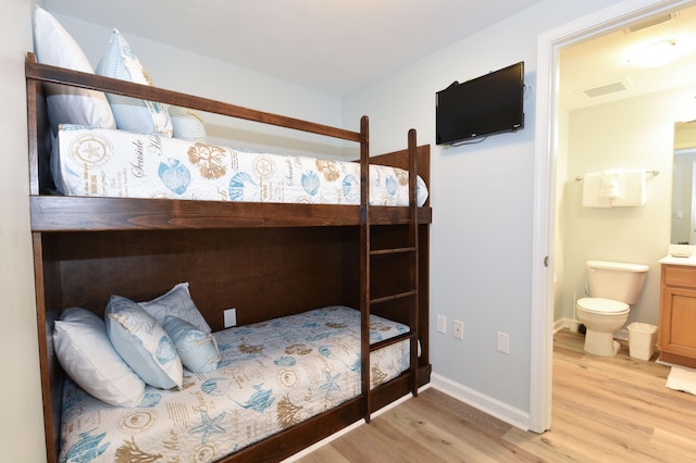 bedroom featuring ensuite bathroom and light hardwood / wood-style floors