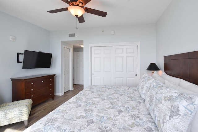 bedroom with wood finished floors, baseboards, visible vents, ceiling fan, and a closet